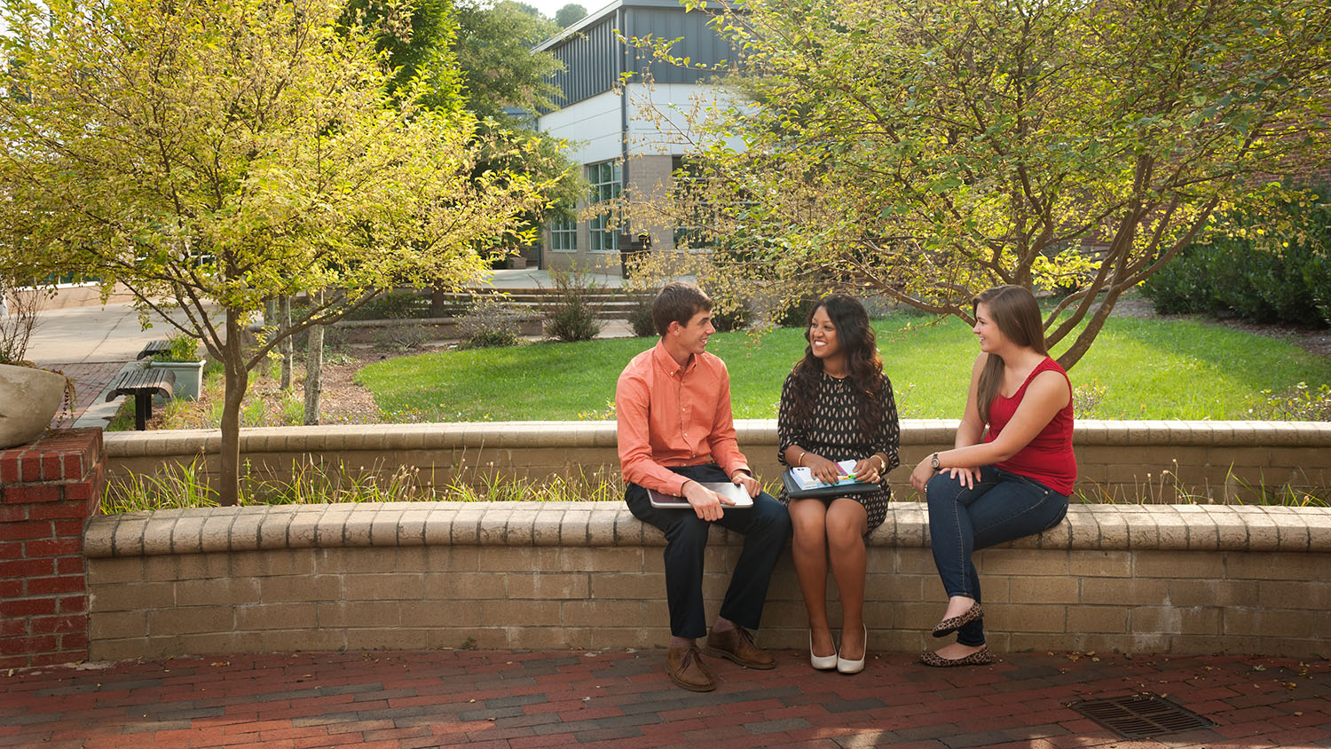 students sitting on brick bench talking